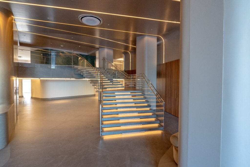 Escada do hall do YachtHouse com corrimão em aço inox e guarda-corpo de vidro